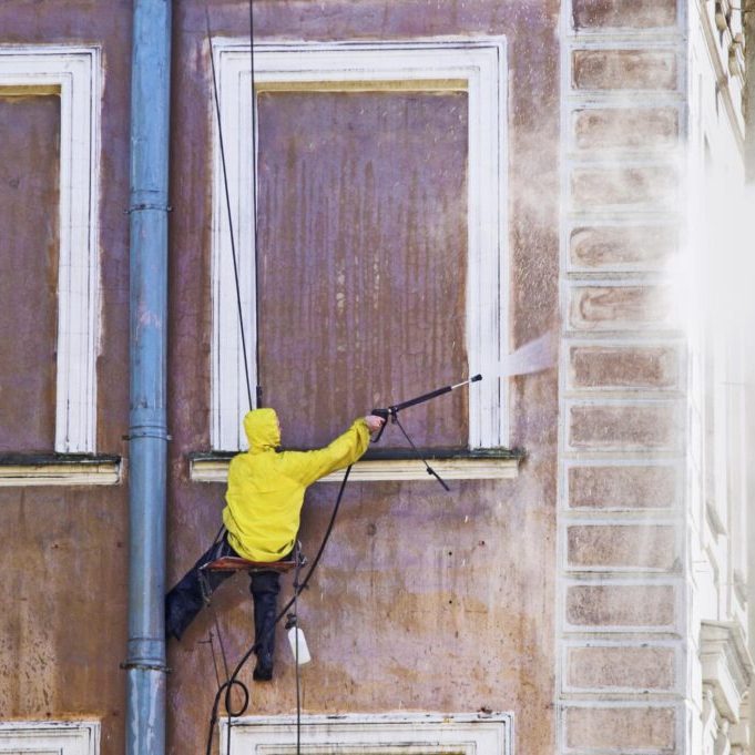 man cleaning the wall of a building
